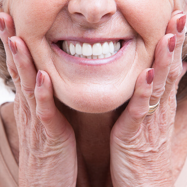 A close-up shot of a mature woman holding her face