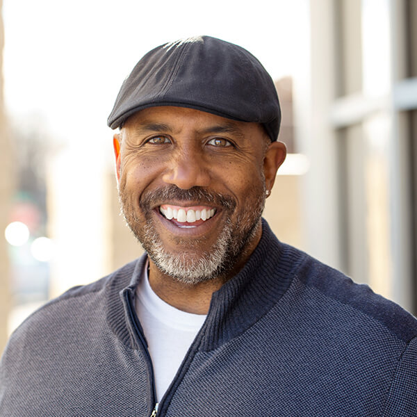 A mature man wearing a hat and smiling