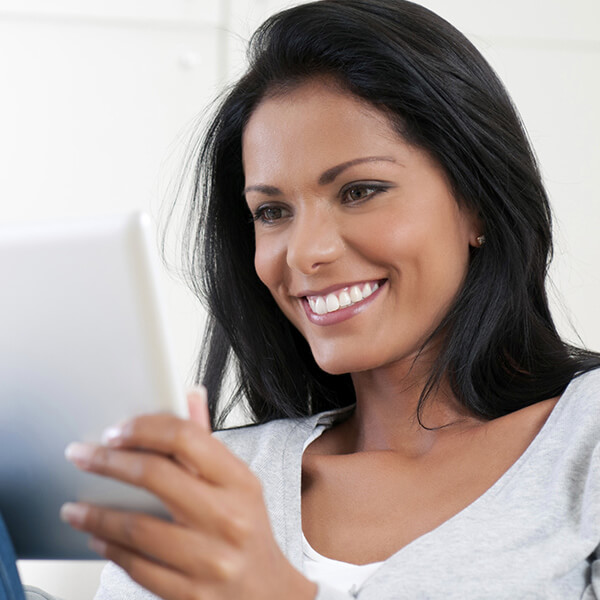 A brunette woman smiling while holding a tablet